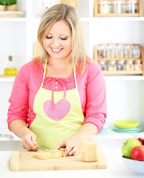 Happy smiling woman in kitchen preparing sandwich — Stock Photo, Image