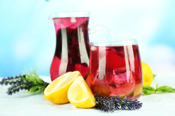 Red basil lemonade in jug and glass, on wooden table, on bright background — Stock Photo, Image