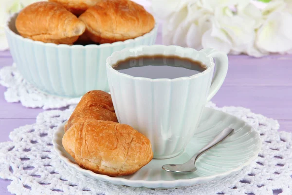 Croissant gustosi e una tazza di caffè in tavola primo piano — Foto Stock