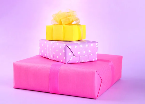 Bright gifts with bows on purple background — Stock Photo, Image