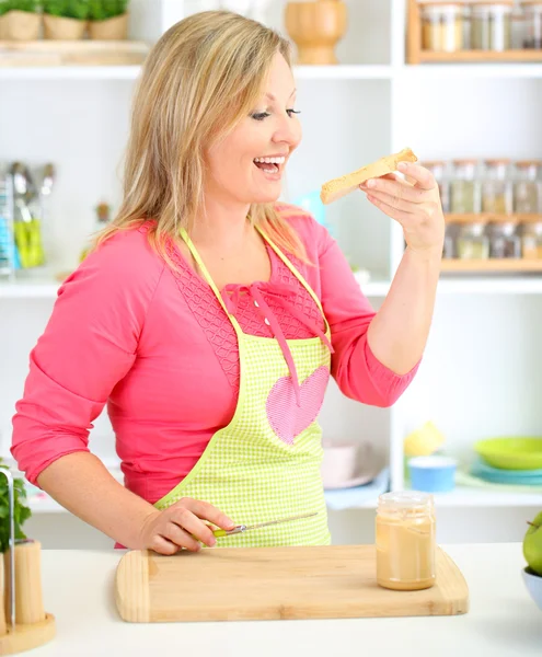 Happy smiling woman in kitchen preparing sandwich — Stock Photo, Image