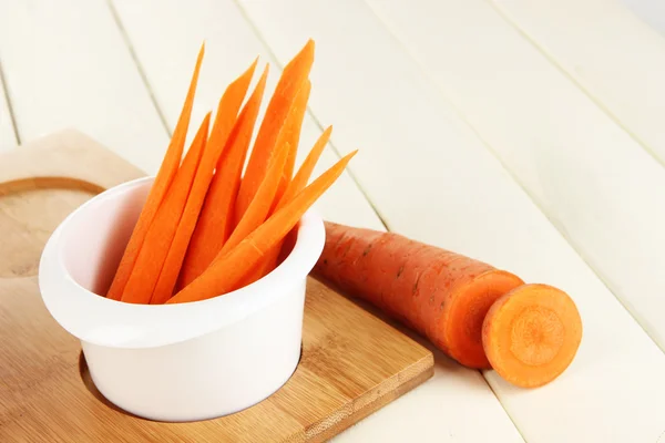 Bright fresh carrot cut up slices in bowl on wooden table close-up — Stock Photo, Image