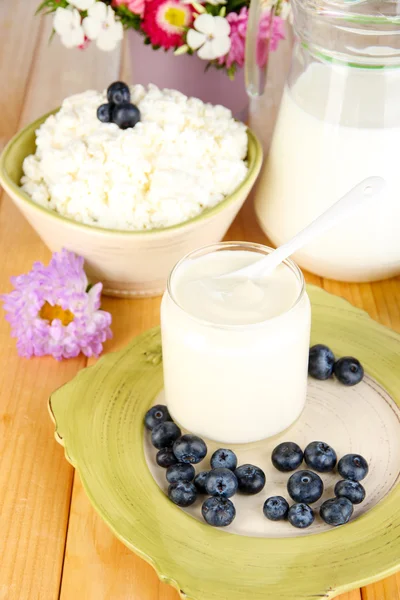 Frische Milchprodukte mit Blaubeeren auf Holztisch in Großaufnahme — Stockfoto