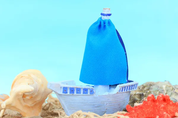 Blaues Spielzeugschiff auf Sand, auf blauem Hintergrund — Stockfoto