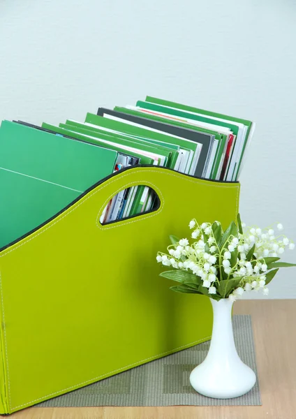 Magazines and folders in green box on bedside table in room — Stock Photo, Image