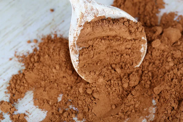 Cacao in polvere in cucchiaio su fondo di legno — Foto Stock
