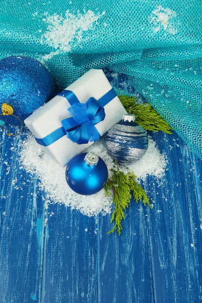 Composition avec boules de Noël, boîte cadeau et neige sur fond en bois couleur — Photo