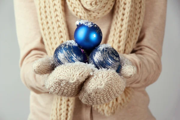 Mani femminili in guanti Albero di Natale palle, su sfondo di colore — Foto Stock