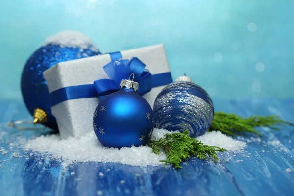 Sammansättning med julen bollar, presentförpackning och snö på färg trä bakgrund — Stock fotografie