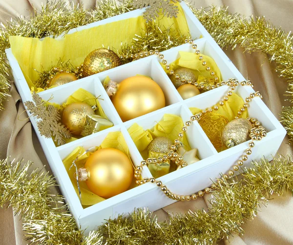 Brinquedos de Natal em caixa de madeira no fundo brilhante — Fotografia de Stock