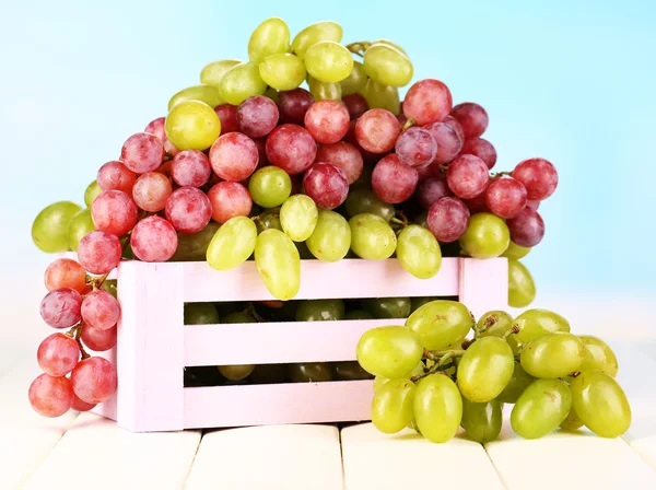 Uvas verdes e roxas maduras em caixa de madeira sobre mesa de madeira sobre fundo natural — Fotografia de Stock