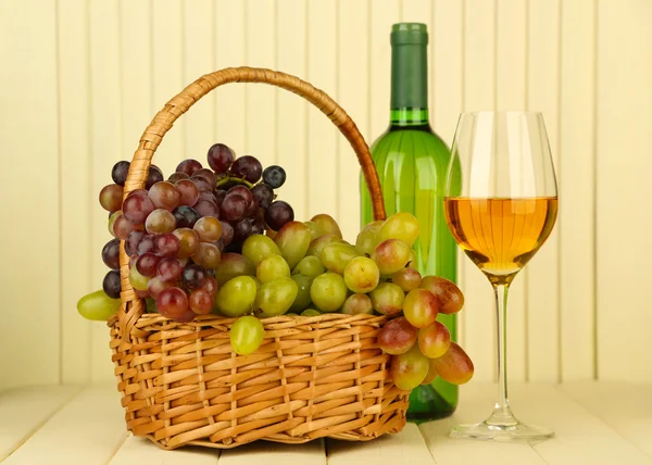 Reife Trauben in Weidenkorb, Flasche und Glas Wein, auf hellem Hintergrund — Stockfoto