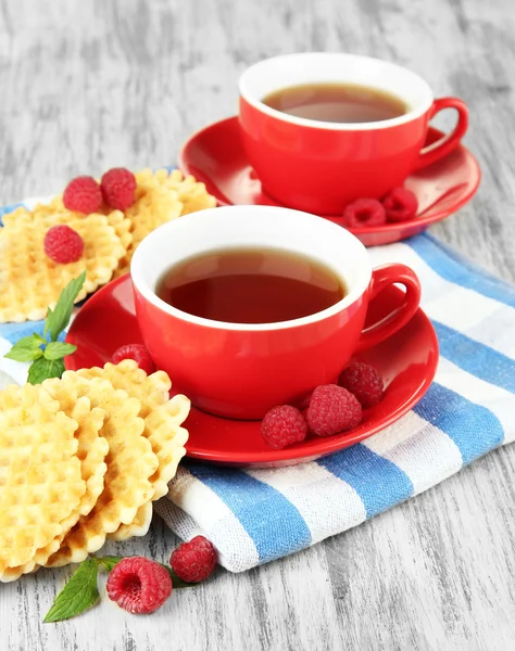 Tazas de té con galletas y frambuesas en primer plano de la mesa —  Fotos de Stock