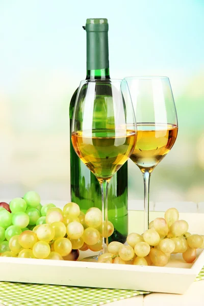 Спелый виноград, бутылка и бокалы вина на подносе, на ярком фоне — стоковое фото