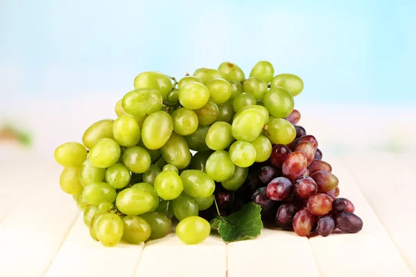 Uvas verdes e roxas maduras em mesa de madeira sobre fundo natural — Fotografia de Stock