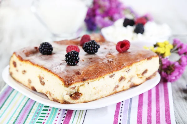 Cheese casserole with raisins on plate on napkin on wooden table close-up — Stock Photo, Image