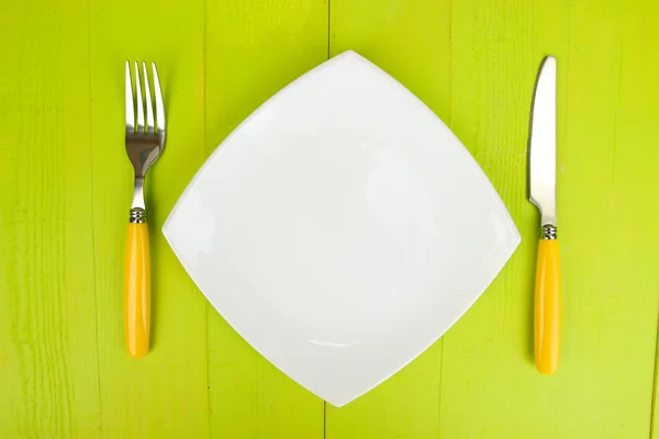 Plate and cutlery on wooden table close-up — Stock Photo, Image