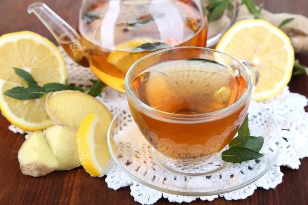 Waterkoker en kopje thee met gember op servet op houten tafel — Stockfoto