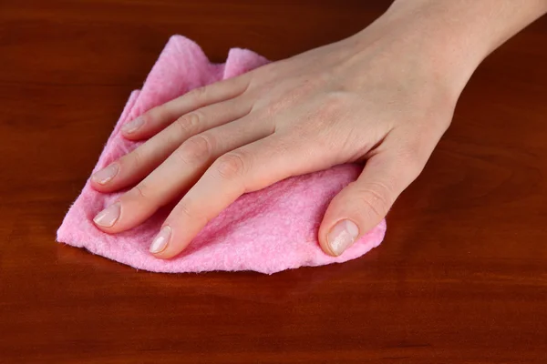 Hand wiping wooden surface with pink rag — Stock Photo, Image