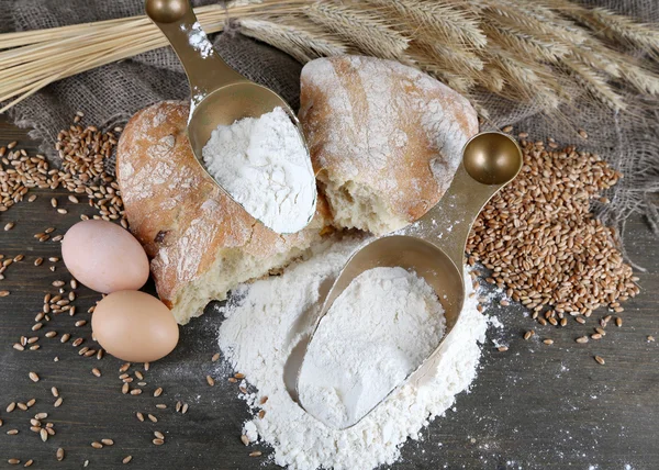 De volkoren meel in scoops op houten tafel — Stockfoto