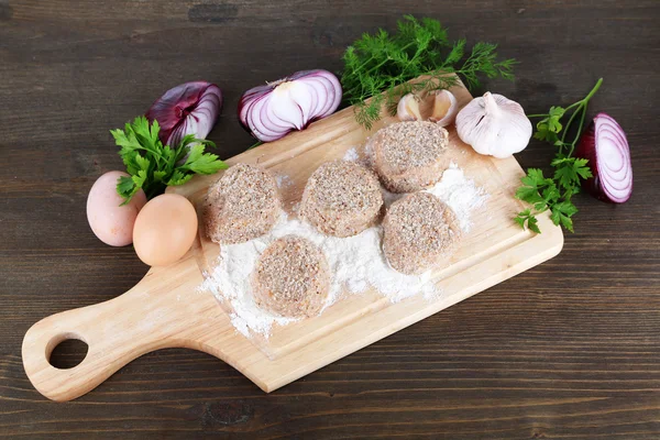 Meat patties on board on wooden table — Stock Photo, Image