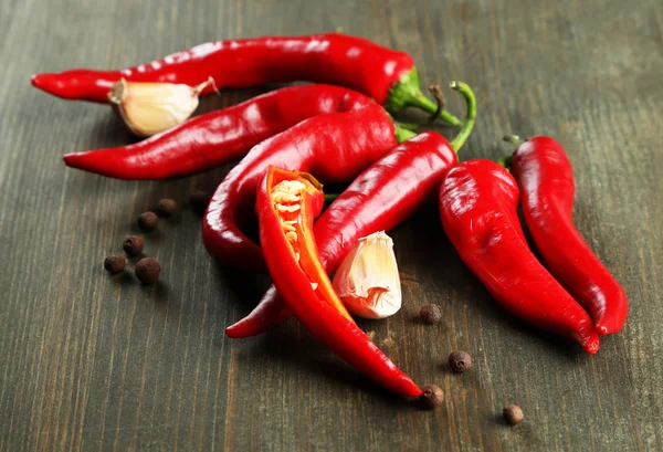 Red hot chili peppers en knoflook, op houten achtergrond — Stockfoto