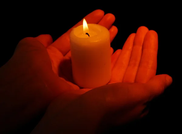 Burning candle in hands isolated on black — Stock Photo, Image
