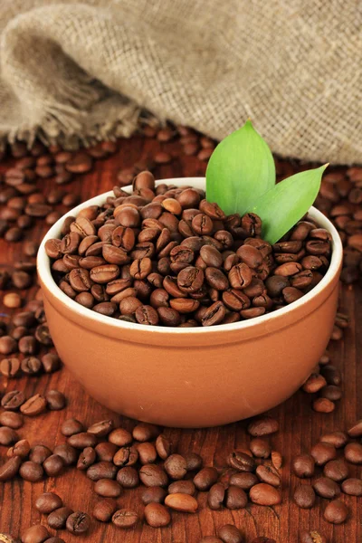 Grãos de café em tigela no fundo de madeira — Fotografia de Stock