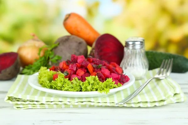 Beet salad on plate on napkin on wooden table on nature background — Stock Photo, Image