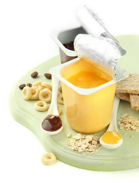 Sobremesas saborosas em copos de plástico abertos e favos de mel, frutas e flocos em tábua de madeira isolada em branco — Fotografia de Stock