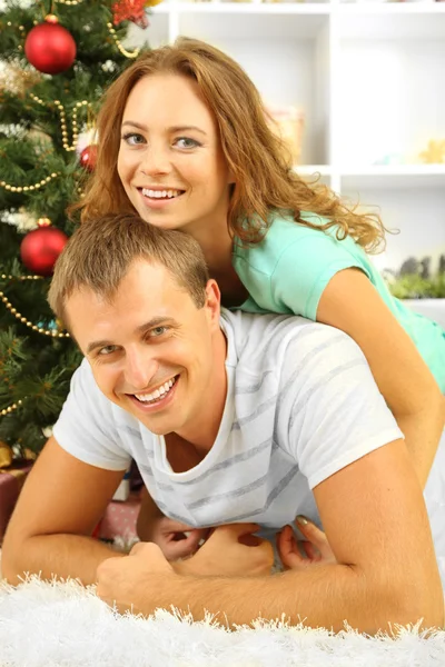 Feliz pareja joven cerca del árbol de Navidad en casa —  Fotos de Stock