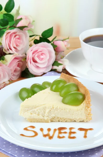 Fetta di cheesecake con bacche d'uva su piatto, su tavolo di legno, su sfondo brillante — Foto Stock