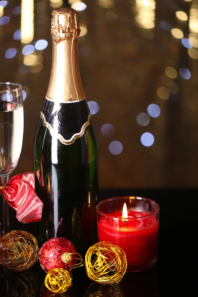 Bottiglia di champagne con vetro e palle di Natale su sfondo luci di Natale — Foto Stock