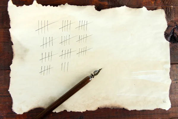 Підрахунок днів, малюючи палички на папері на дерев'яному фоні — стокове фото