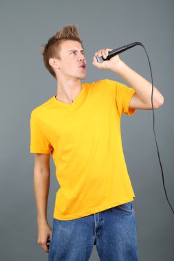 yakışıklı genç gri arka plan üzerinde şarkı söylüyor.