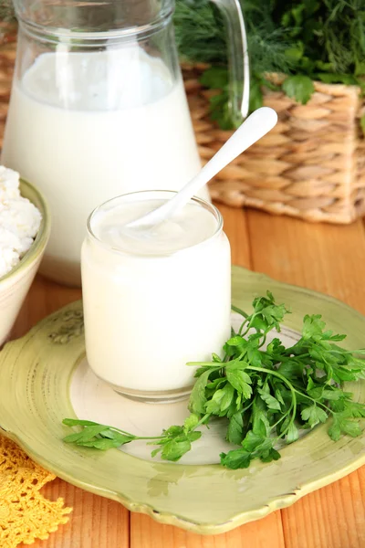 Färska mjölkprodukter med gröna på träbord på naturliga bakgrund — Stockfoto