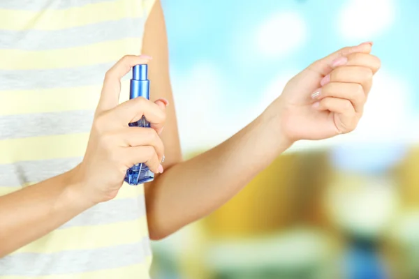 Mulher testando perfume em fundo brilhante — Fotografia de Stock