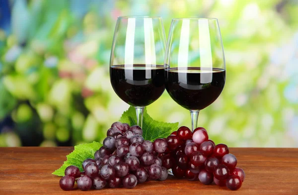 Rijpe druiven en glazen wijn, op lichte achtergrond — Stockfoto