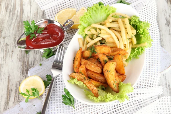 French fries and home potatoes on plate on board on napkin on wooden table — Stock Photo, Image