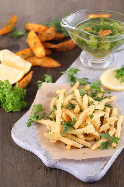 Pommes frites på ritpapper ombord på träbord — Stockfoto