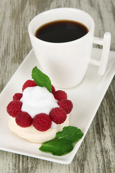 Вкусный безе торт с ягодами и чашкой кофе, на деревянном столе — стоковое фото