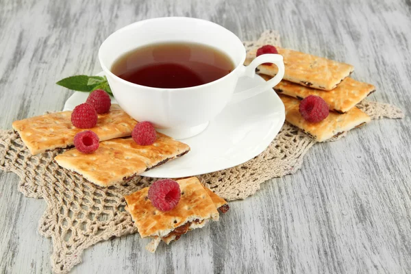 Cup of tea with cookies and raspberries on table close-up