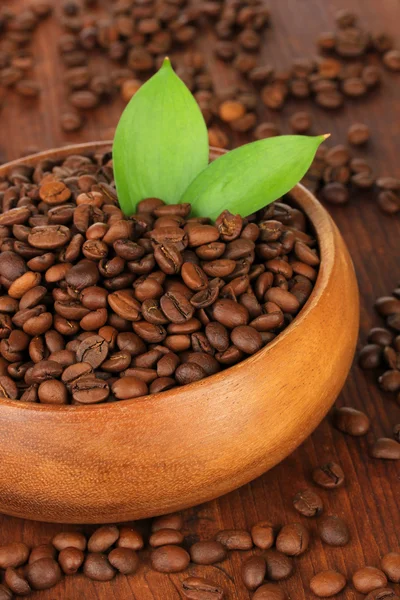 Granos de café en tazón sobre fondo de madera — Foto de Stock