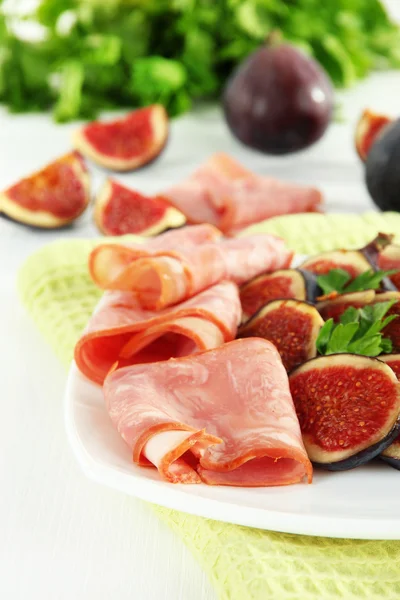 Tasty figs with ham on white wooden table — Stock Photo, Image