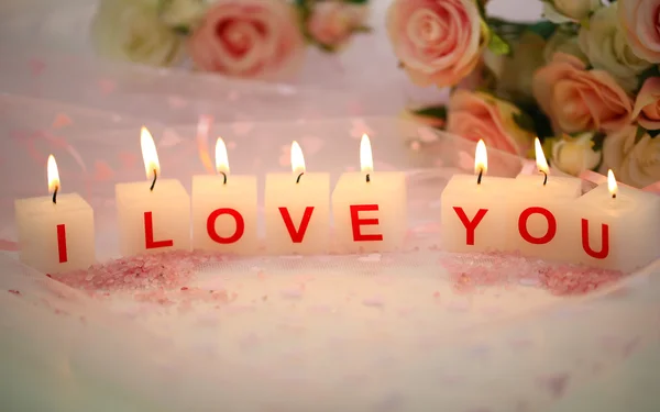 Kerzen mit bedrucktem Zeichen ich liebe dich, auf farbigem Stoffhintergrund — Stockfoto