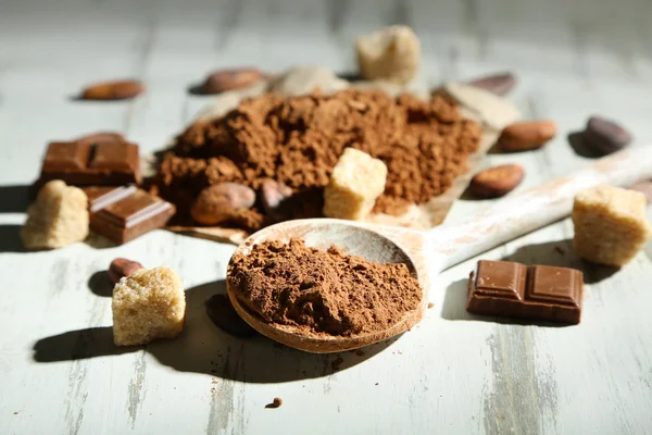 Cocoa powder in spoon on wooden table — Stock Photo, Image