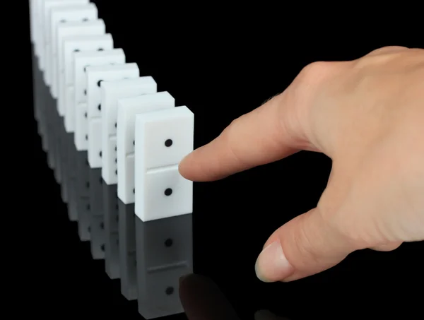 Mão empurrando dominó isolado no preto — Fotografia de Stock