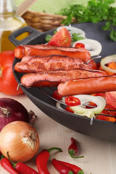 Delicious sausages with vegetables in wok on wooden table close-up — Stock Photo, Image