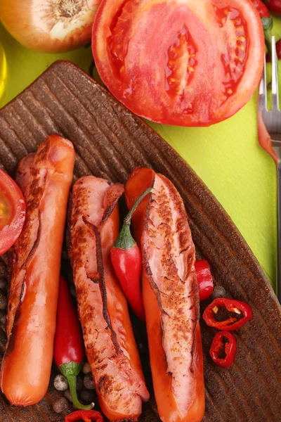 Salsichas deliciosas com legumes no prato na mesa de madeira close-up — Fotografia de Stock