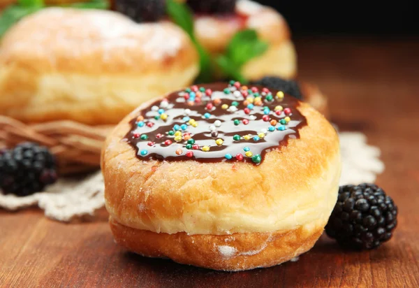Leckere Donuts mit Schokolade und Beeren auf Holztisch — Stockfoto
